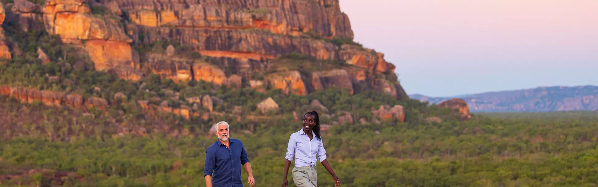 People walking along rock with Ubirr in the background