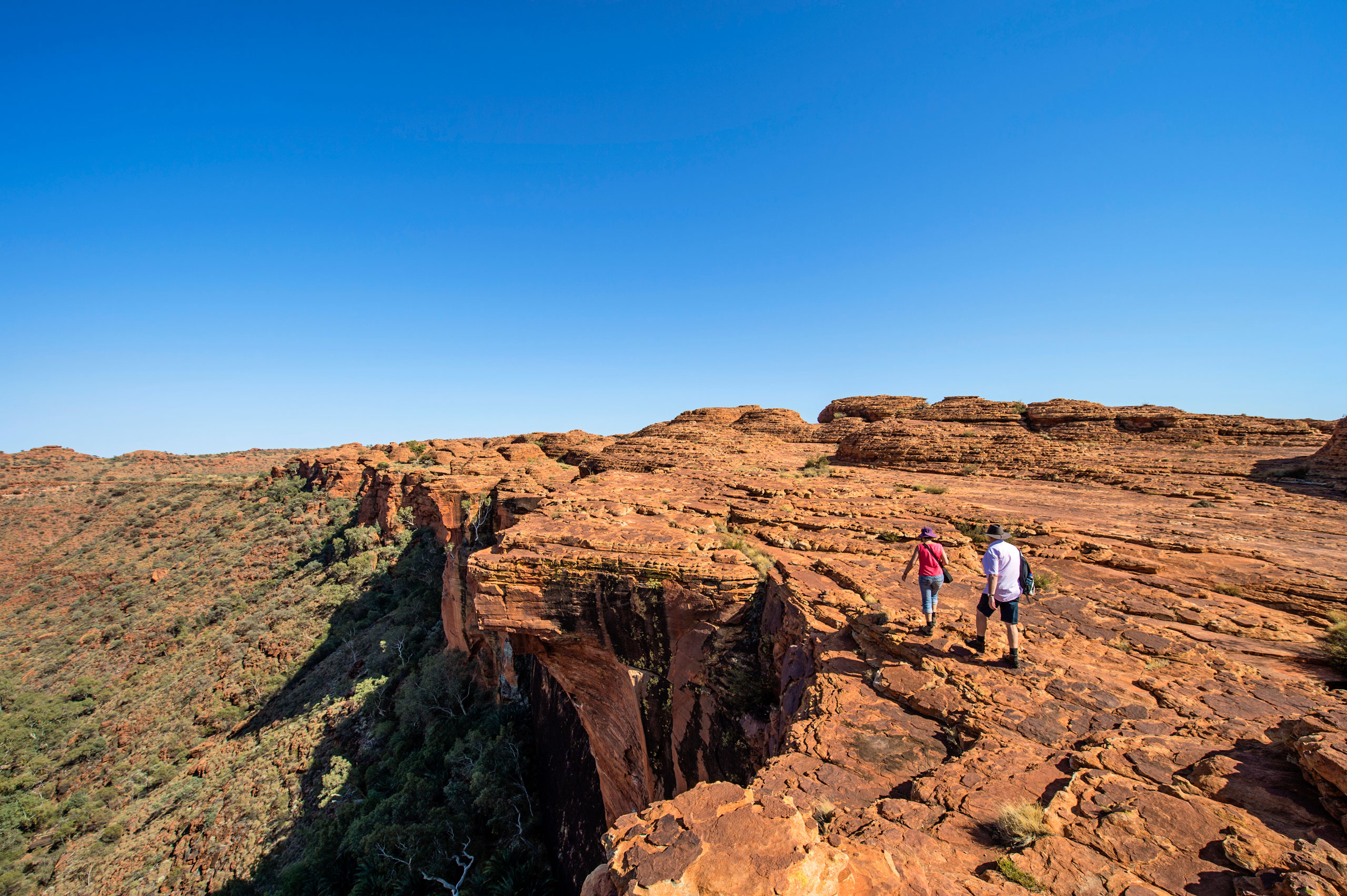 A couple of people walking on top of a cliff