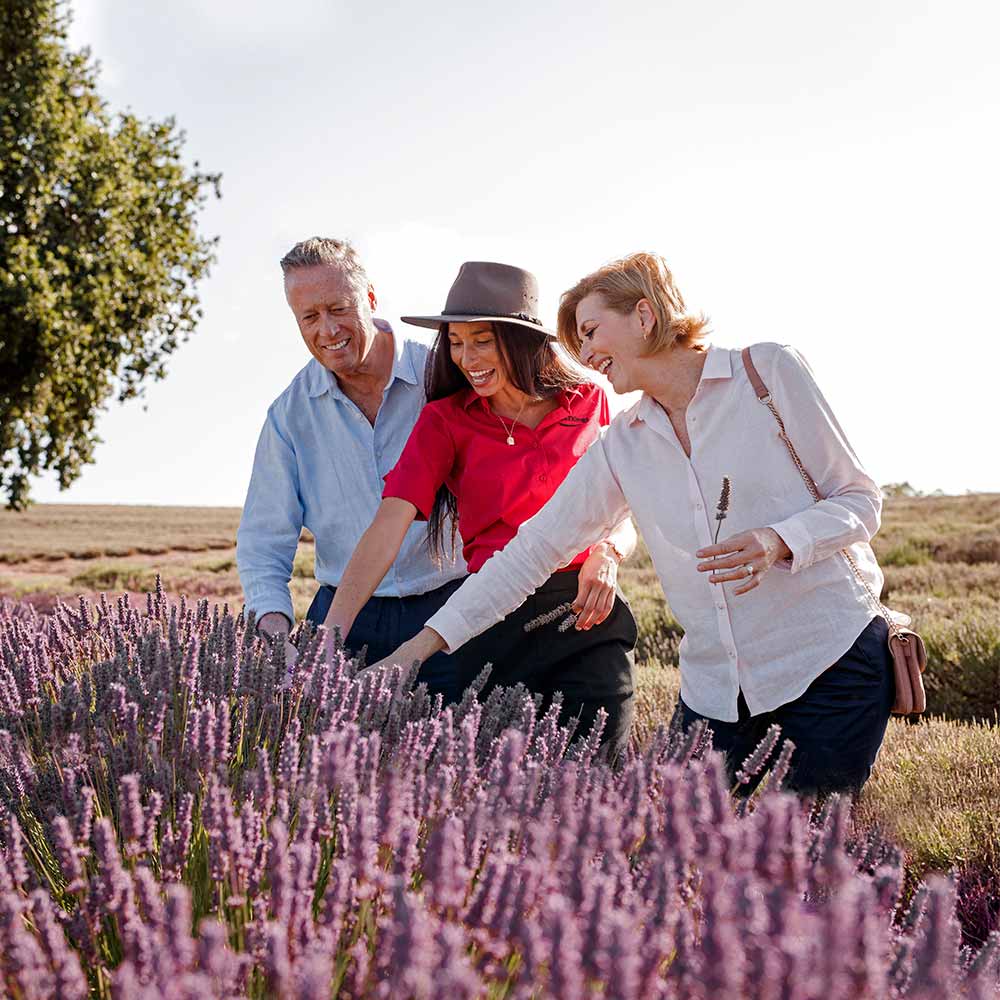 A group of people smiling and standing in a field of flowers