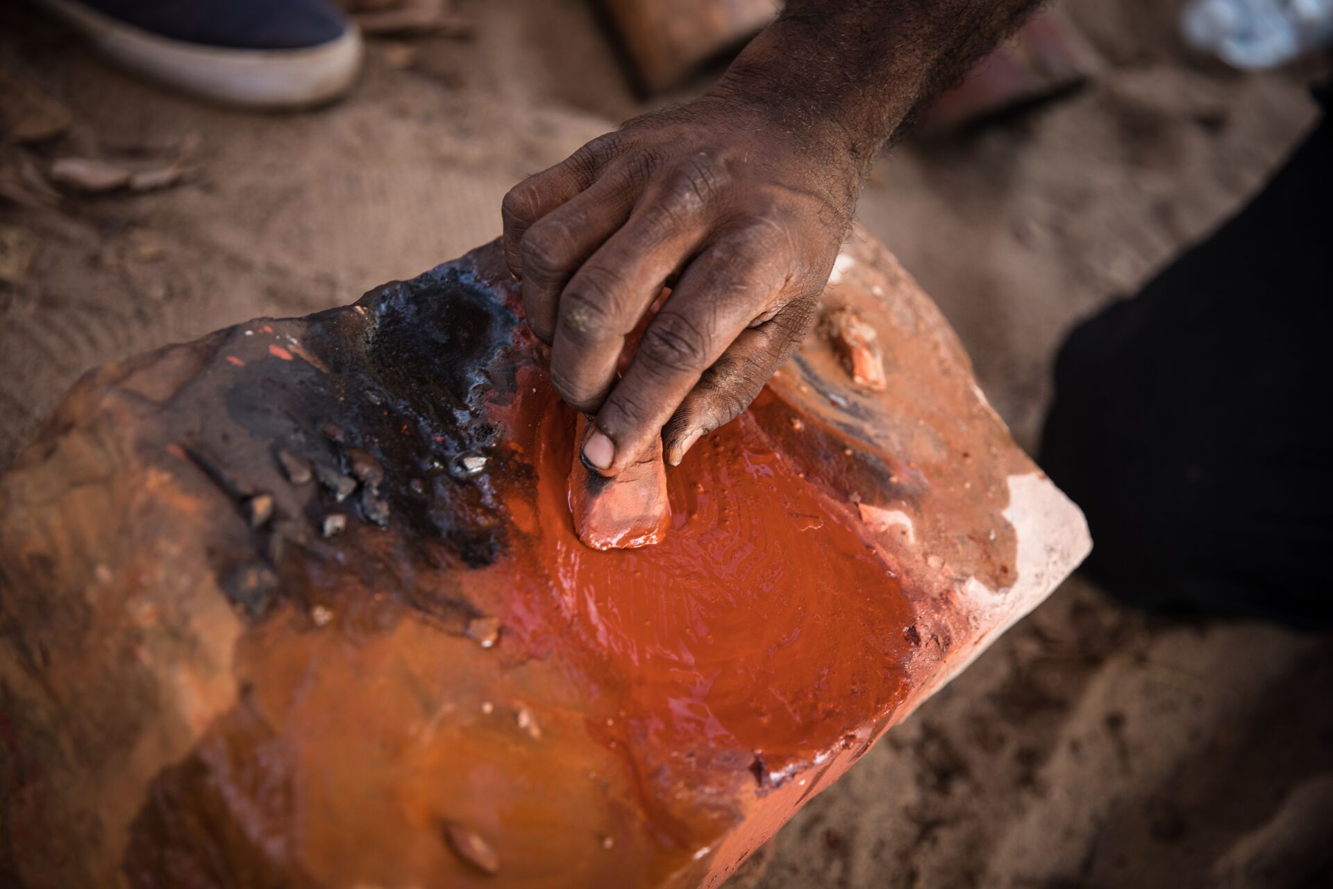 A person is holding a piece of red clay