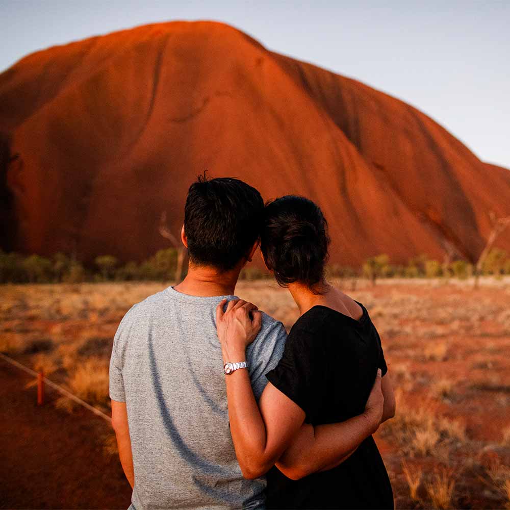 A man and a woman hugging in front of a mountain