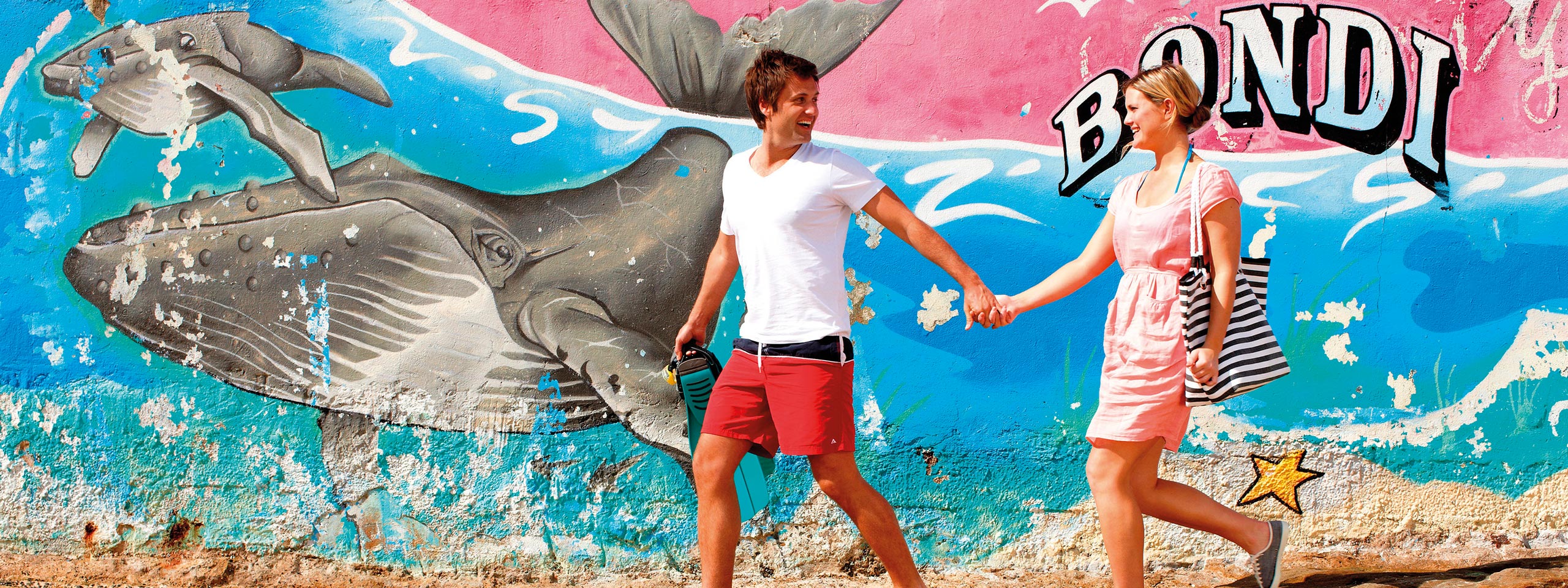 A couple with Bondi Beach street art in the background