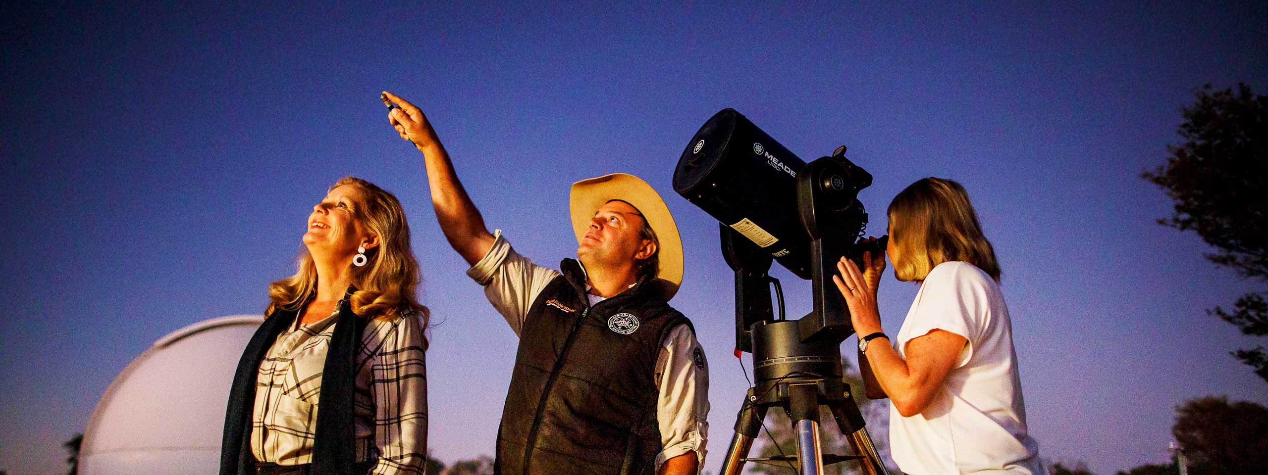 Three people staring at the dark sky