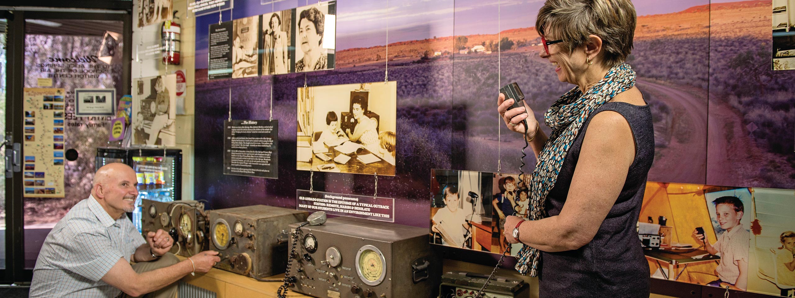 A woman standing next to a man in front of a wall with old devices