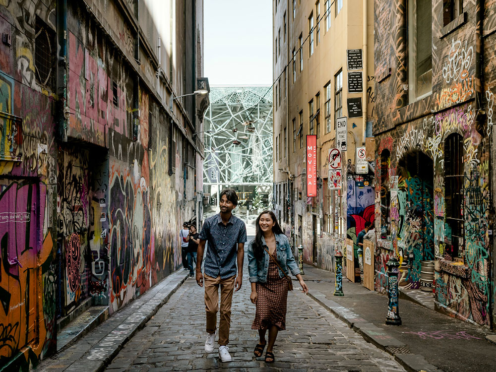 A man and a woman walking down a street among grafitti painted walls