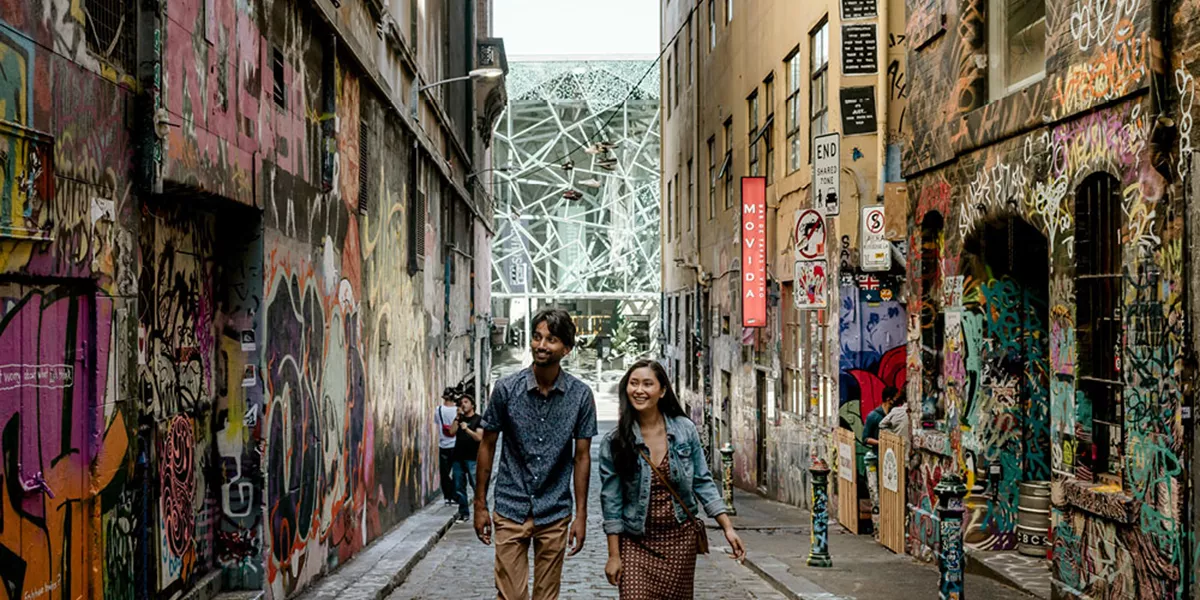 A man and a woman walking down a street among grafitti painted walls