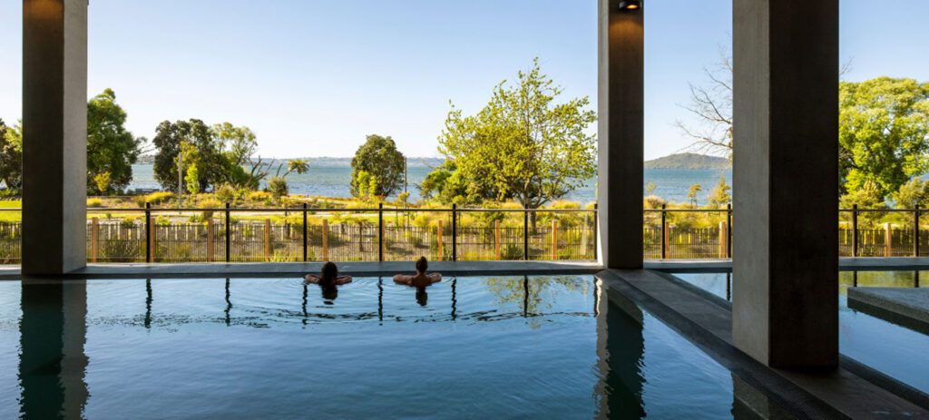 Outdoor thermal pools at Wai Ariki Hot Springs and Spa, surrounded by natural timber architecture in Rotorua. At Wai Ariki Hot Springs, you can relax and reconnect, surrounded by Māori culture and nature. This two-hour spa experience helps relax your body, calm your mind, and restore balance.