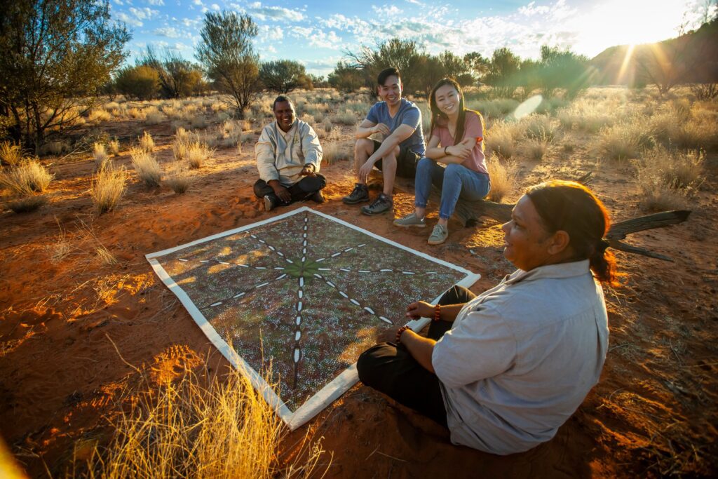 Two people sitting and learning from Indigenous guides during the Karrke Aboriginal Cultural Experience in the Northern Territory.