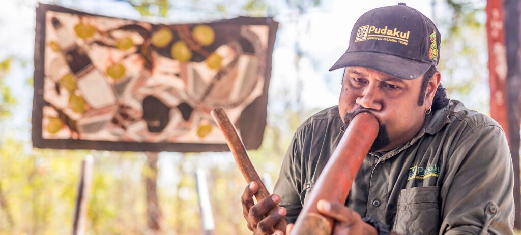 Man playing a didgeridoo during a Pudakul Aboriginal Cultural Tour.