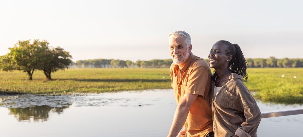 Two people on a cruise boat overlooking Yellow Water Billabong, with wetlands stretching into the distance