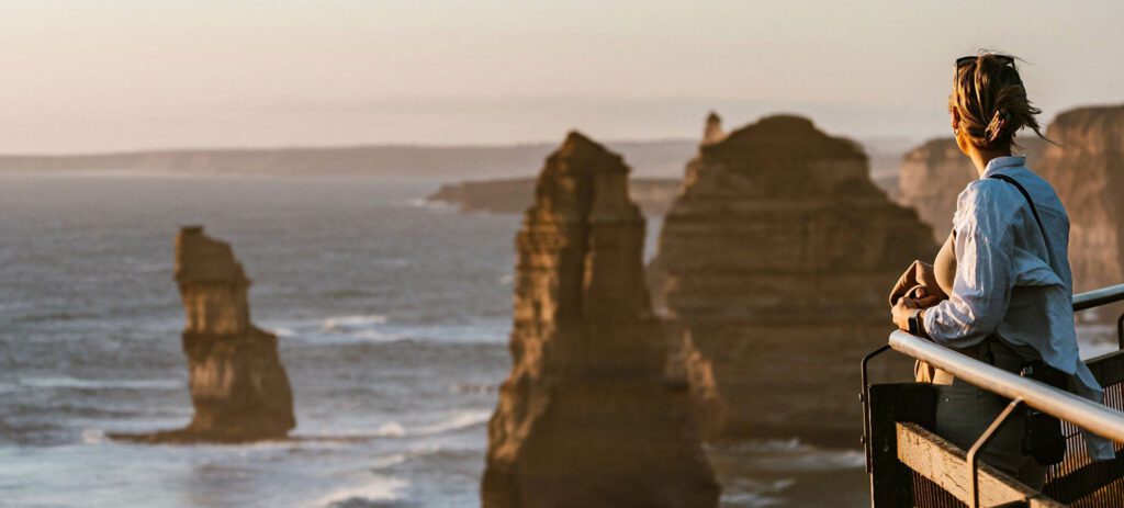 Coastal rock stacks at Gros Morne National Park viewed from a lookout with a person standing by a railing.