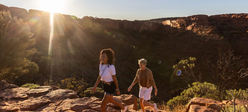 Travellers walking along the Kings Canyon rim at sunrise in the Northern Territory