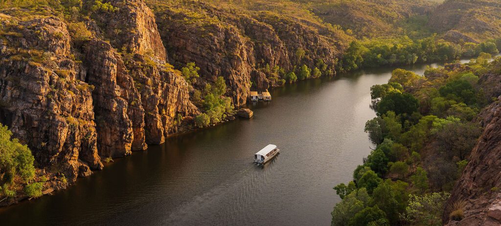 Boat cruising through Nitmiluk Gorge surrounded by towering sandstone cliffs