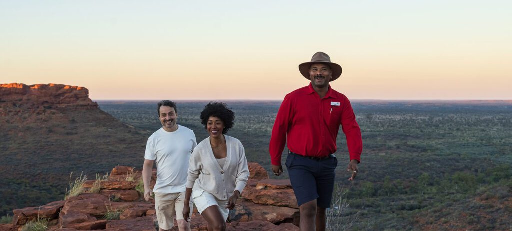 Two smiling guests follow their AAT Kings Travel Director along Kings Canyon walks