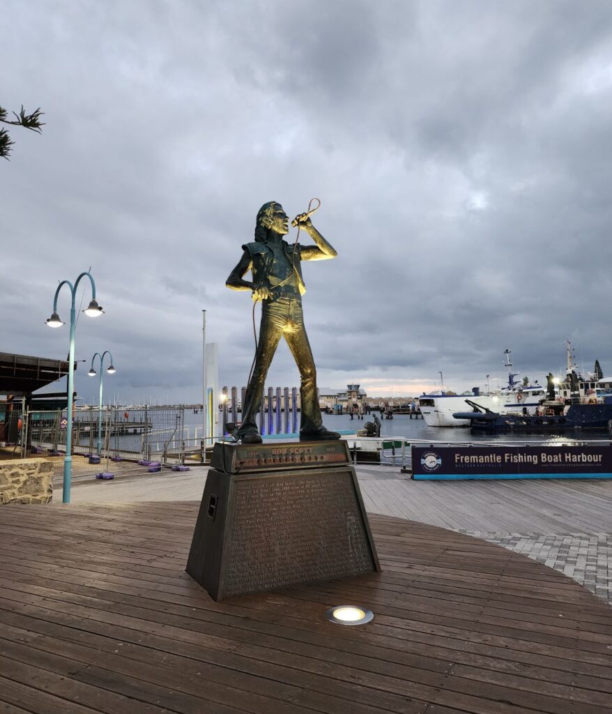A statue of ACDC singer Bon Scott against an overcast sky