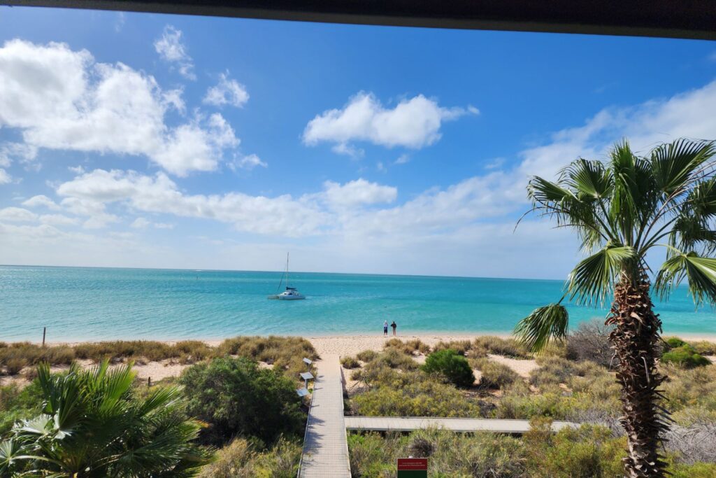 A view over a beach with bright blue water and white sand